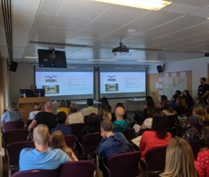 Crowd sits for presentation on juvenile dermatomyositis.
